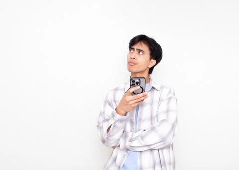 Young man looking confused while checking his smartphone, expressing doubt .. Stock Photos