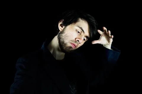 Young man looking down with his left hand up doing a pose Foto stock