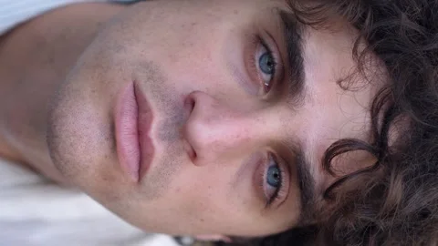 Young man looking down, then turning to camera with intense melancholic gaze Video stock 277611553
