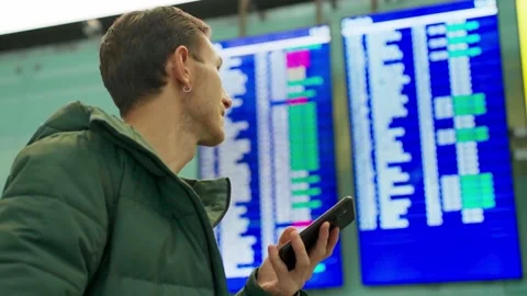 Young man looking at flight schedule at airport. Checking airline departure Stock Footage 169823161