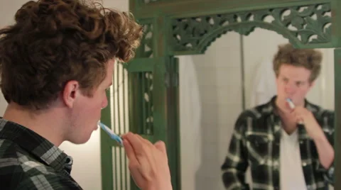 Young man looking at himself in the mirror, brushing his teeth Stock Footage 40843245