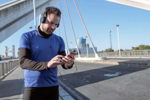 Young man looking at his cell phone to listen to music while running through Foto stock