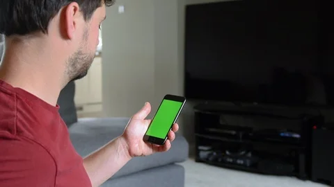 Young man looking at his phone, with a green screen Stock Footage 92284575