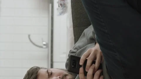 Young man looking at his smartphone while lying on the sofa is using smartphone Stock Footage 196123468