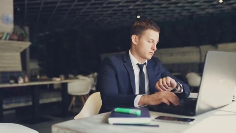 Young man is looking at his watch In Cafe Stock Footage 75980567