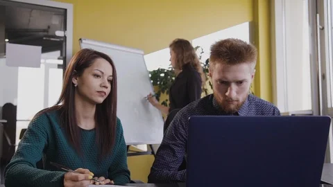 Young man is looking at laptop screen, sitting at table in office. Stock Footage 119458426