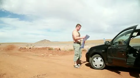 Young man looking at a map on the car hood Vídeos de archivo 10842401