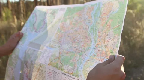  Young man looking a map in a forest at sunset Stock Footage