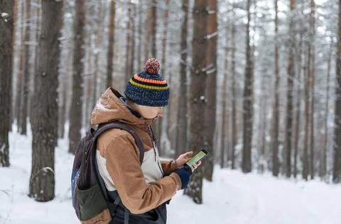 Young man  looking at map on smartphone hiking in winter snowy forest Stock Photos