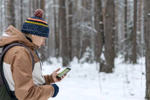 Young man  looking at map on smartphone hiking in winter snowy forest Stock Photos