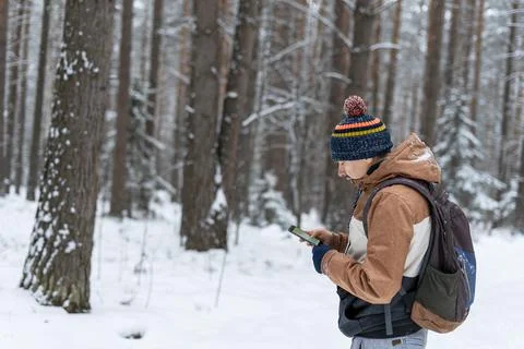 Young man  looking at map on smartphone hiking in winter snowy forest Foto stock