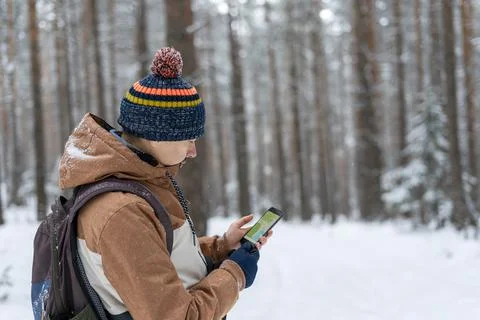 Young man  looking at map on smartphone hiking in winter snowy forest Stock Photos