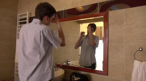 Young man looking in a mirror and fixing his hair  Stock Footage 68386267