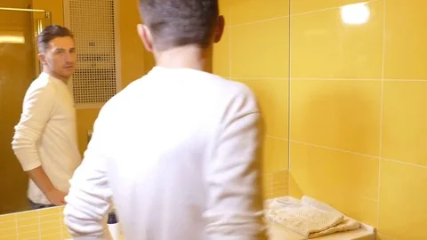 Young man looking at the mirror in the bathroom Stock Footage 71777182