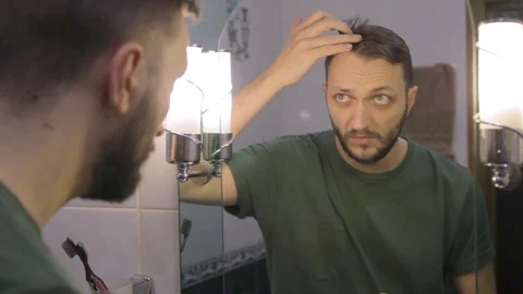 Young man looking at mirror, checking hair for lice Stock Footage 104022053