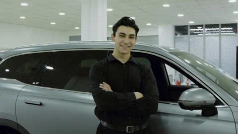Young man looking at a new car model in a luxury auto showroom Stock Footage 323174705