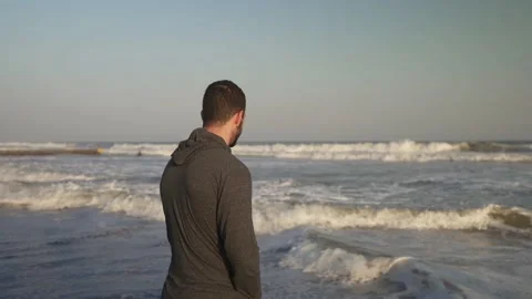 Young man looking out at Atlantic Ocean waves, Folly Beach South Carolina, 4K Stock Footage 218638467