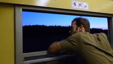Young man looking out of a open window on a train Stock Footage 84988964