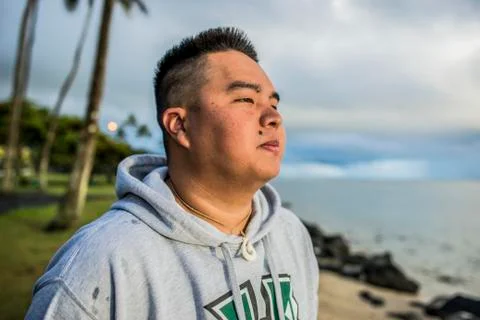 Young man looking out at sunrise from Kaaawa beach, Oahu, Hawaii, USA Stock Photos