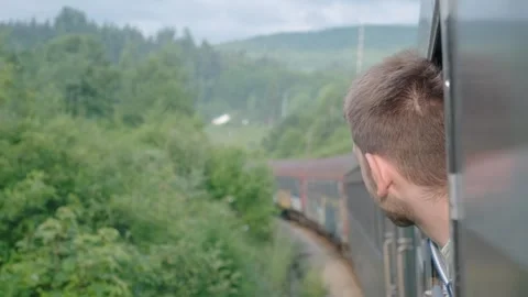 Young man looking out of train window while traveling by railway through Balkans Stock Footage 251004509