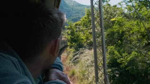 Young man looking out of train window while traveling by railway. Male traveler Stock Footage 269062774