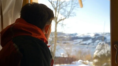 Young man looking out the window at beautiful landscape in winter at the mo.. Video stock 72027843
