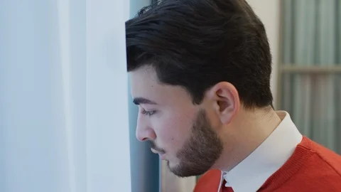 Young man looking out the window Stock Footage 99940589