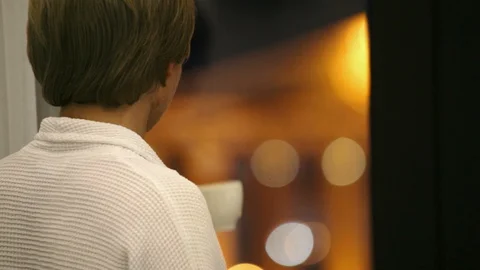 Young man looking out window at building and drinking coffee Stock Footage 105930318
