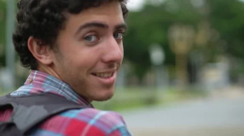 Young man looking over shoulder at camera while walking Stock Footage 63296199