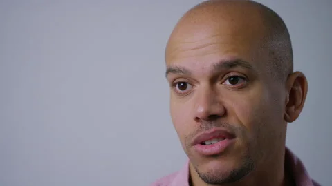 Young man looking sad as he talks to someone off camera in an interview setup Video stock 145973773