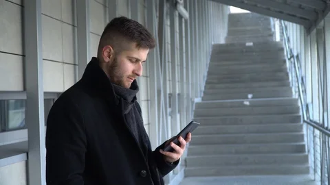 A young man is looking at a smartphone. A man looks at the phone and smiles. Stock Footage 119200709