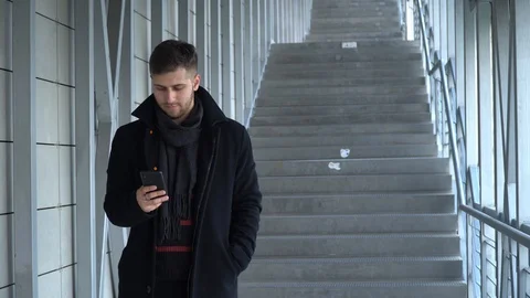 A young man is looking at a smartphone. A man looks at the phone and smiles. Stock Footage 119200772
