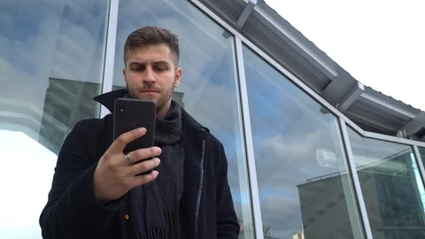 A young man is looking at a smartphone. A man looks at the phone and smiles. Stock Footage 119201008