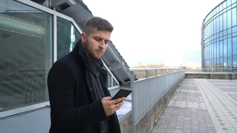 A young man is looking at a smartphone. A man looks at the phone and smiles. Stock Footage 119201039