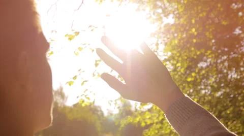 Young man looking at the sun shining through his fingers Stock Footage 67253878