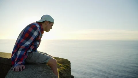 Young man looking at sunset view, ocean and sunlight in the background Stock Footage 146631720