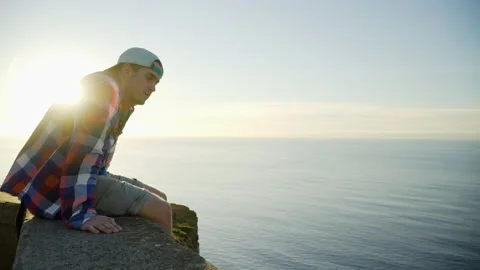 Young man looking at sunset view, ocean and sunlight in the background Stock Footage 146631782