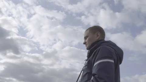 Young man looking through binoculars. Sky clouds background 4k Stock Footage 85121443
