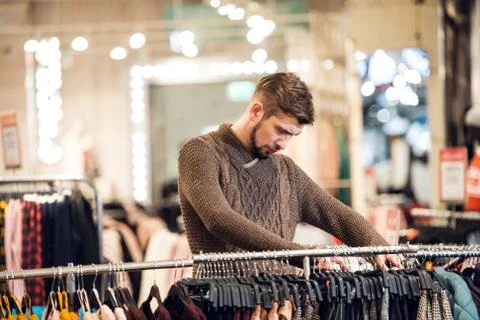 A young man looking through the clothes on a rail, a scene at a Stock Photos