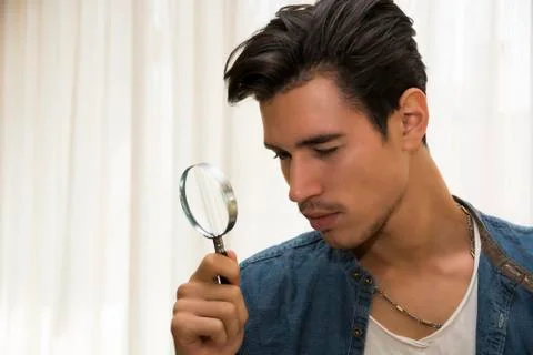 Young man looking through a magnifying glass Foto stock