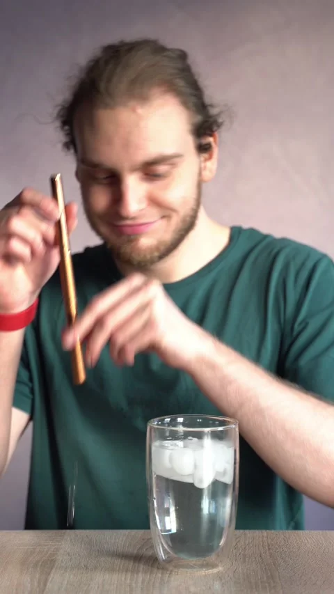 Young man looking through metal straw then drinking ice water Stock Footage 229651207