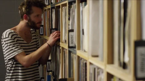 Young man looking through vinyl record collections at music shop Stock Footage