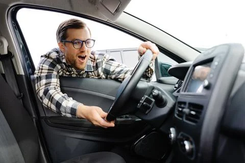 Young man looking through window inside new car, checking it before purchas.. Stock Photos