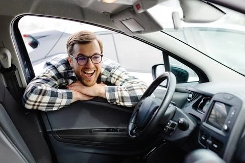Young man looking through window inside new car, checking it before purchas.. Stock Photos