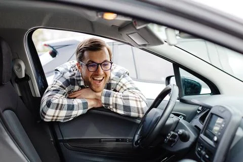 Young man looking through window inside new car, checking it before purchas.. Stock Photos