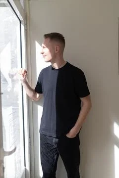 Young man looking through window enjoying sunlight Stock Photos
