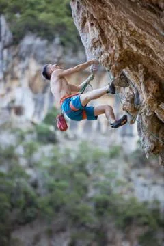 Young man looking up while climbing challenging route on cliff Stock Photos