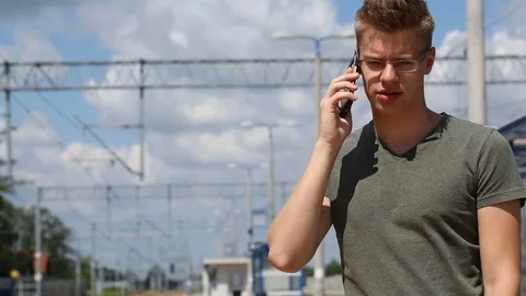 Young man looks angry while speaking with someone on cellphone on the train  Stock Footage 78655500