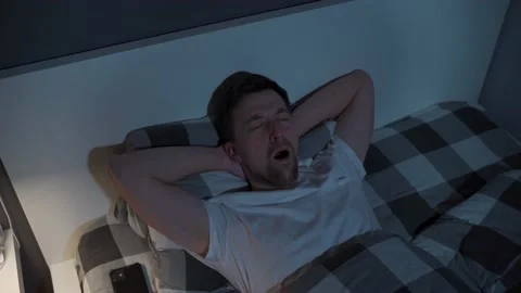 Young man looks at the ceiling at night while lying in bed instead of sleeping Stock Footage 155004165