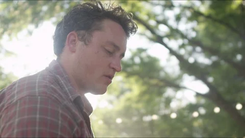 Young man looks down at the grill at a backyard barbecue with a lens flare Video stock 125726667